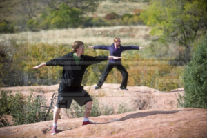 Man and Woman Standing On Rock Outstretching Arms Doing Yoga